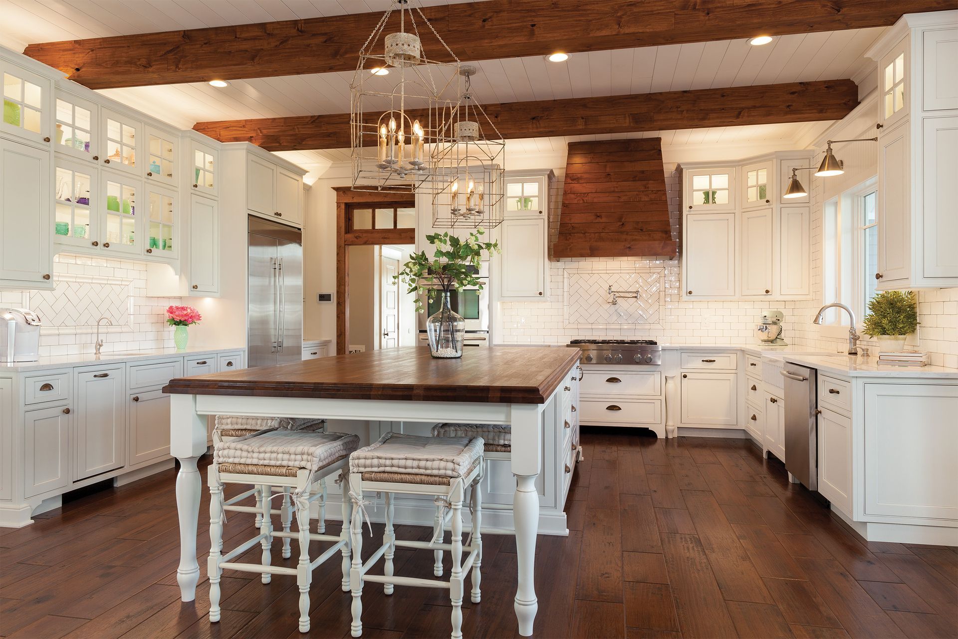 A kitchen with white cabinets and wooden beams