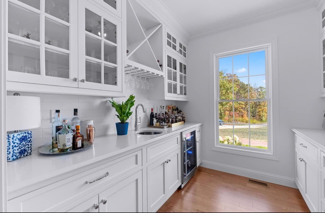 A kitchen with white cabinets, a sink, and a window.