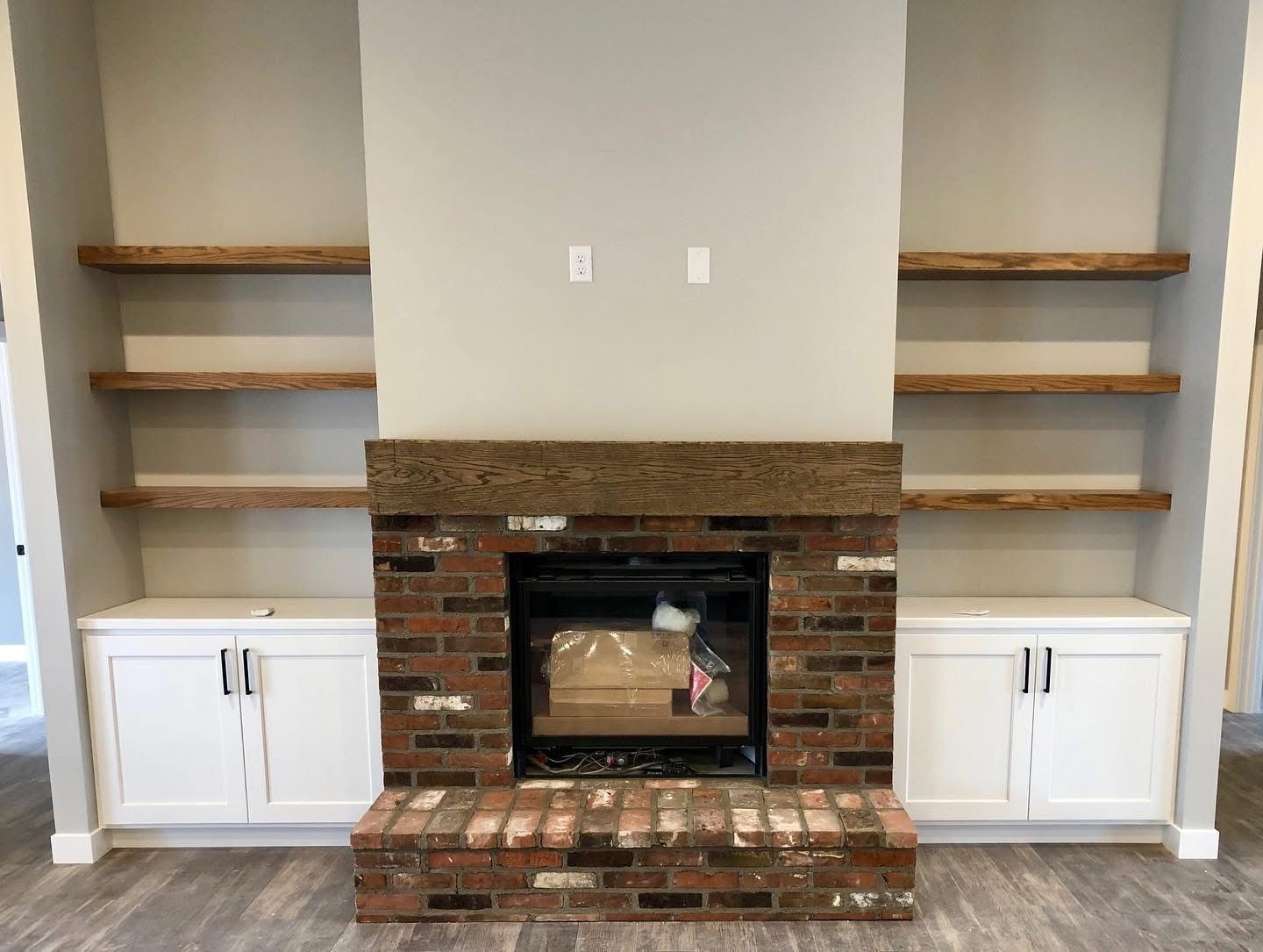 A living room with a brick fireplace and shelves