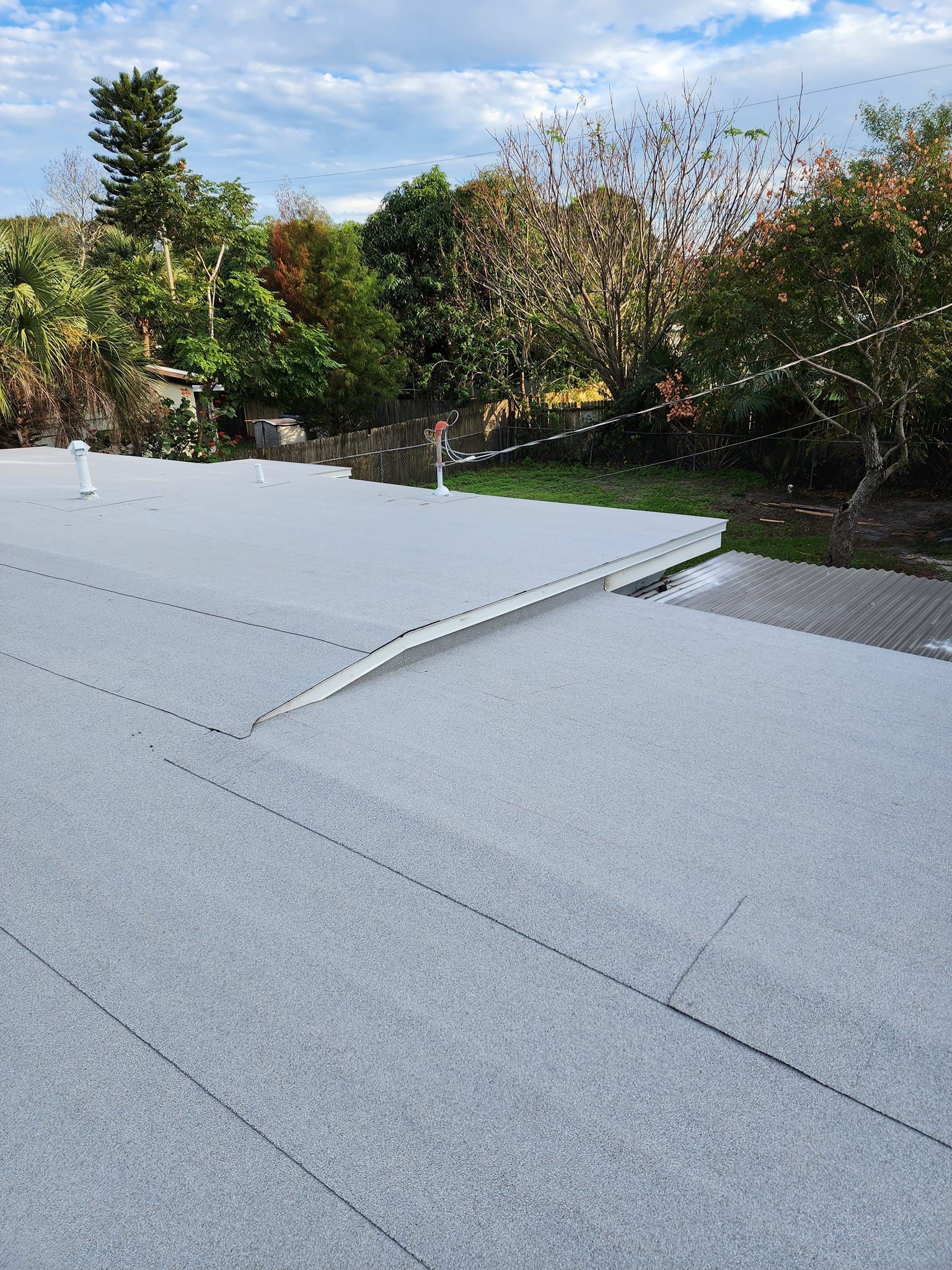 A white roof with trees in the background and a blue sky in the background.