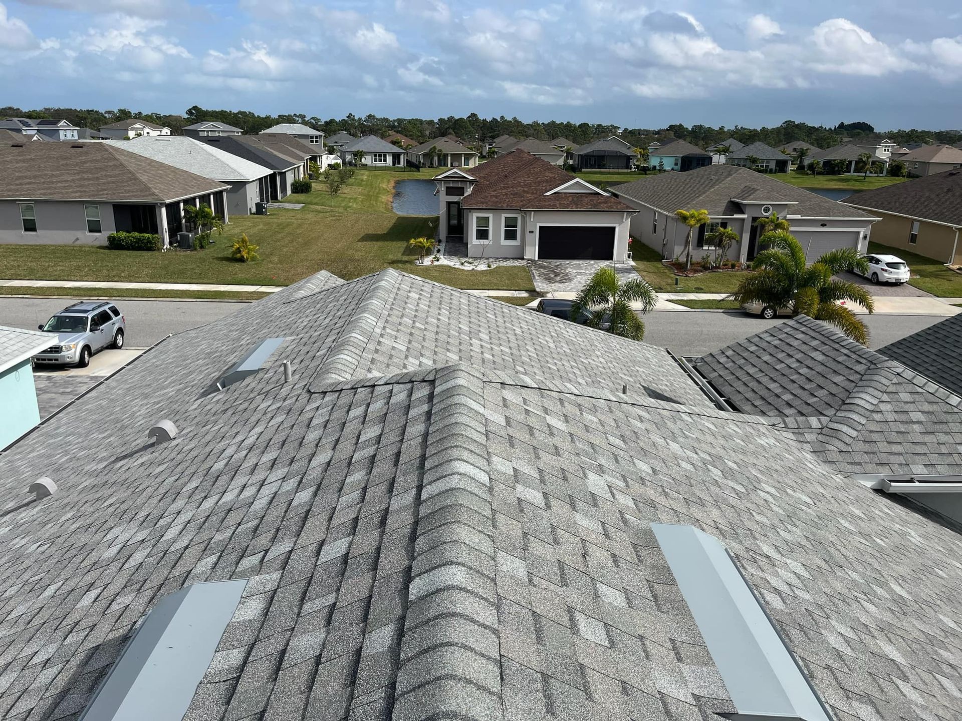An aerial view of a residential neighborhood with a roof in the foreground