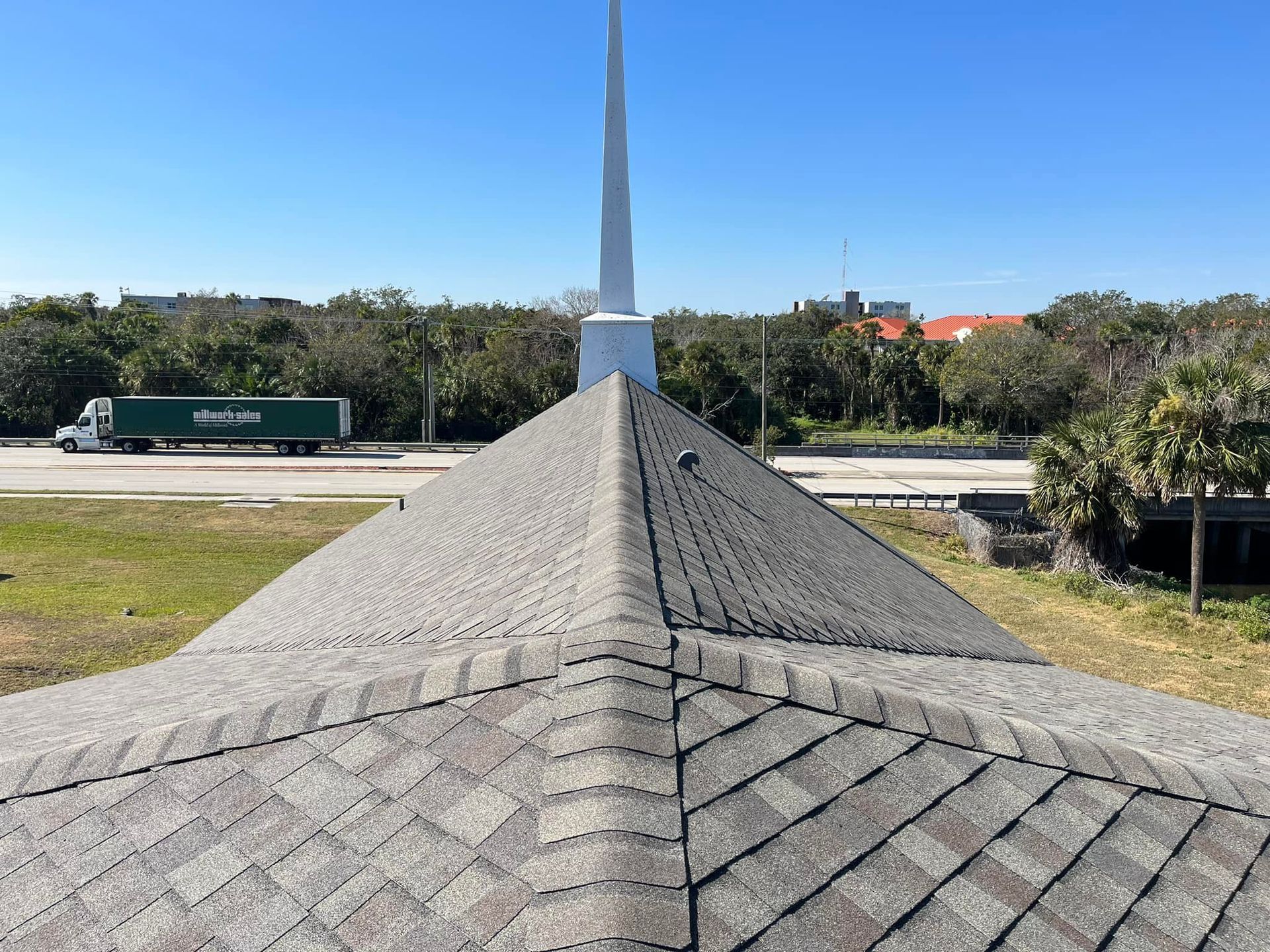 A green truck is driving down a highway next to a roof.