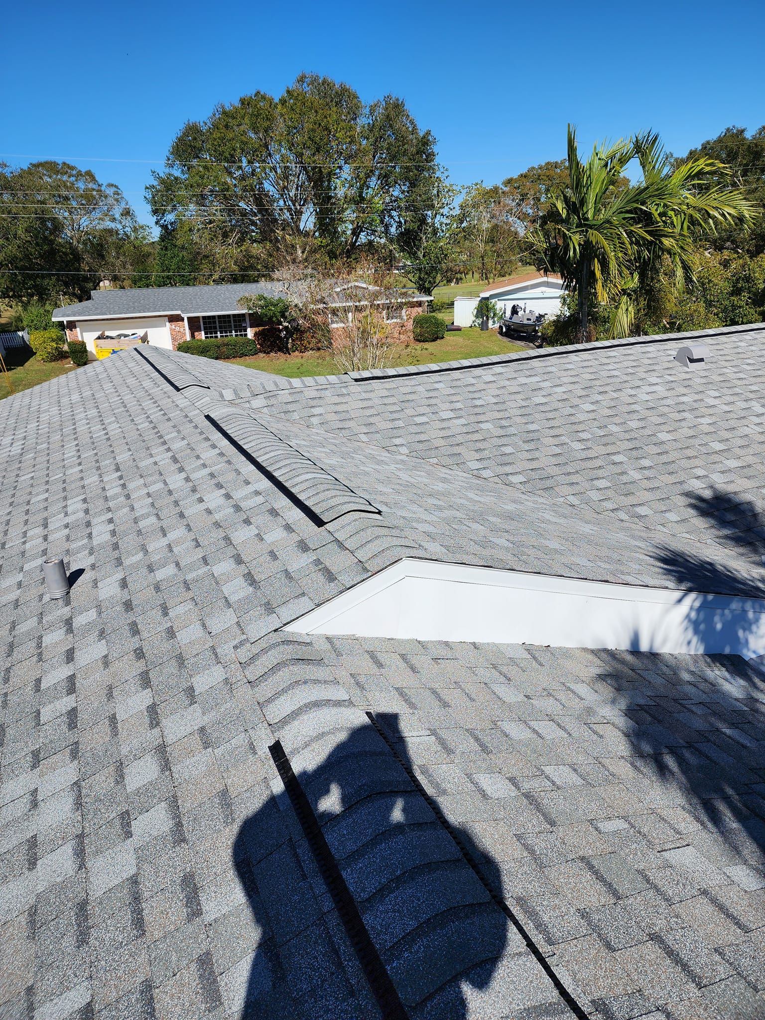 A roof with a hole in it and a shadow of a person on it.