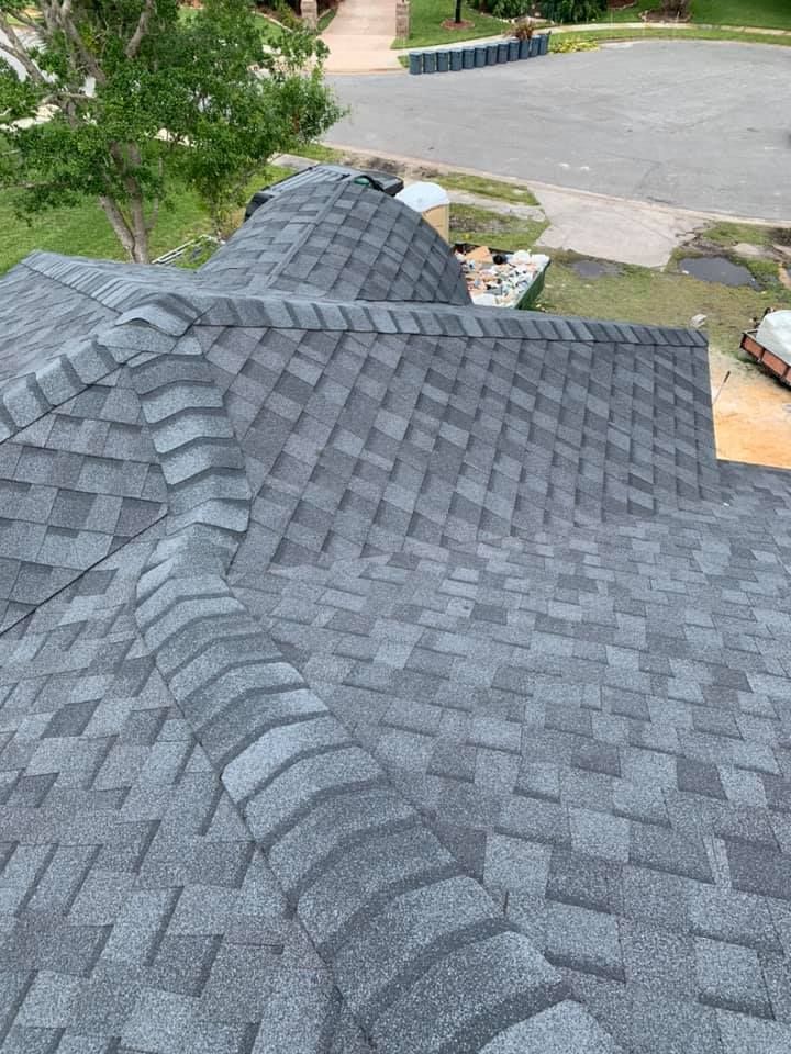 A roof with a lot of shingles on it is being installed on a house.