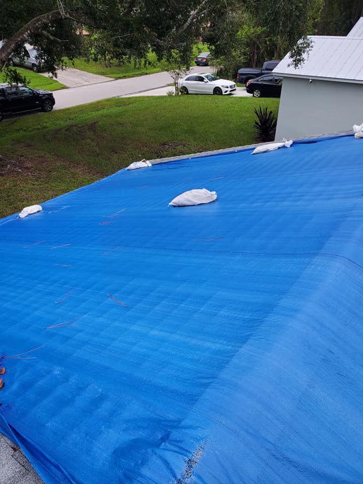 A blue tarp is covering the roof of a house.