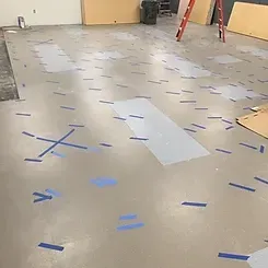 A room with a lot of tape on the floor and a ladder.