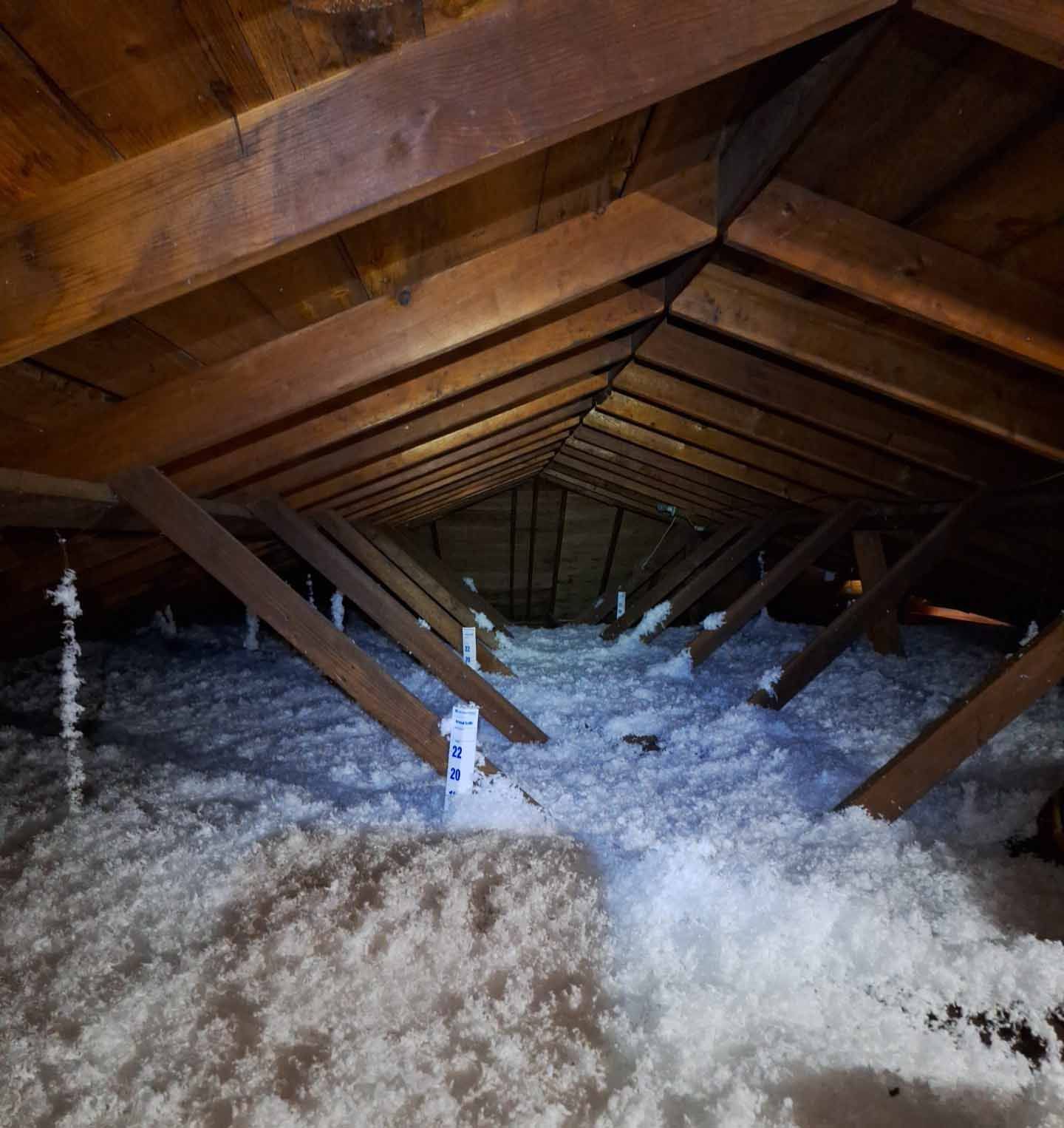 An attic with a lot of insulation and wooden beams