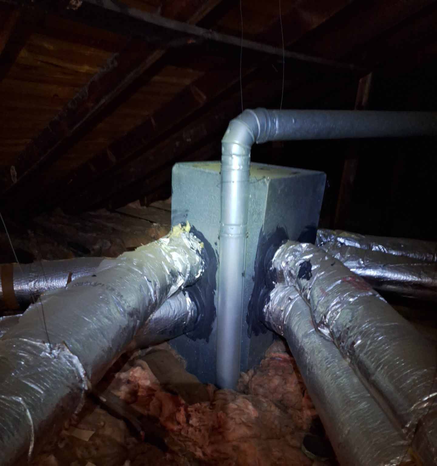 A bunch of pipes are connected to each other in an attic
