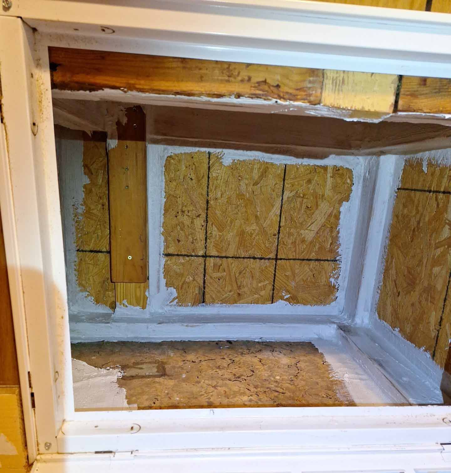 The inside of a white cabinet with a wooden floor