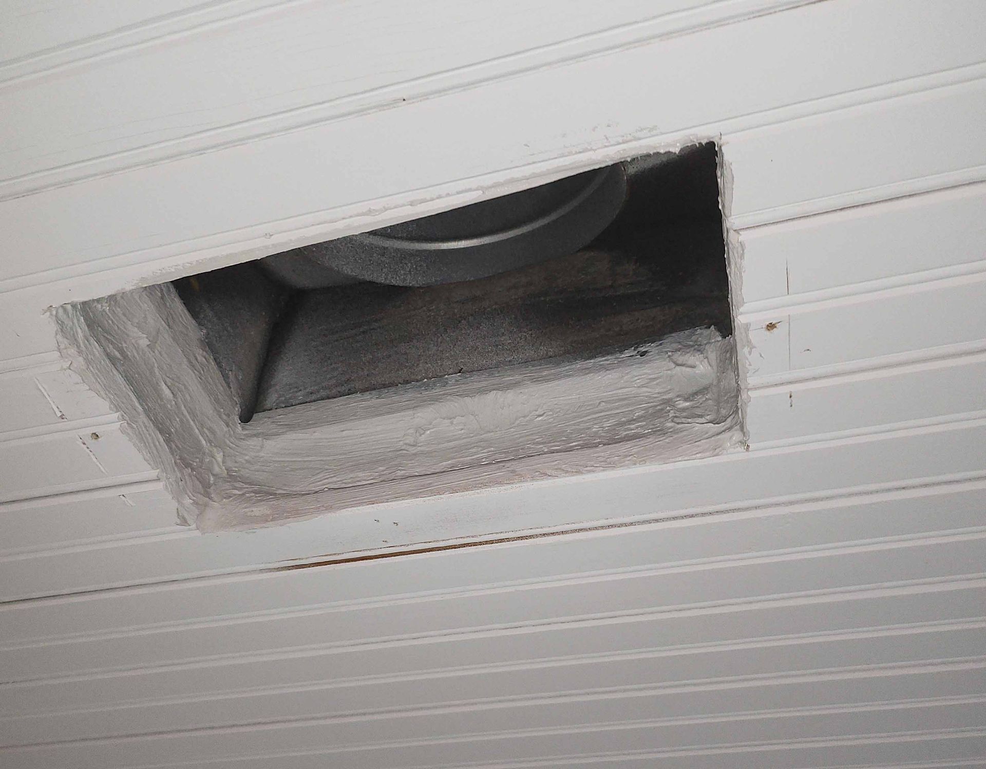 A hole in the ceiling with a fan coming out of it.