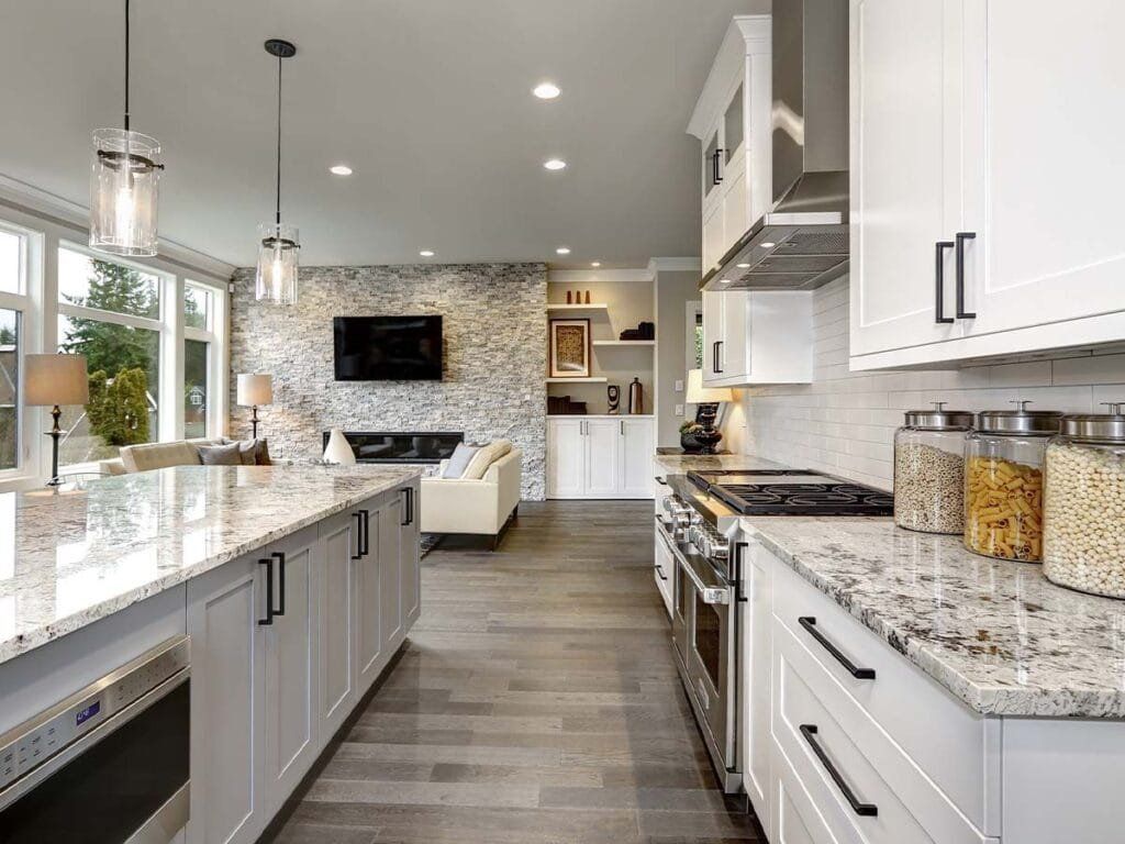 Modern kitchen with white cabinets, granite countertops, and open to living area.