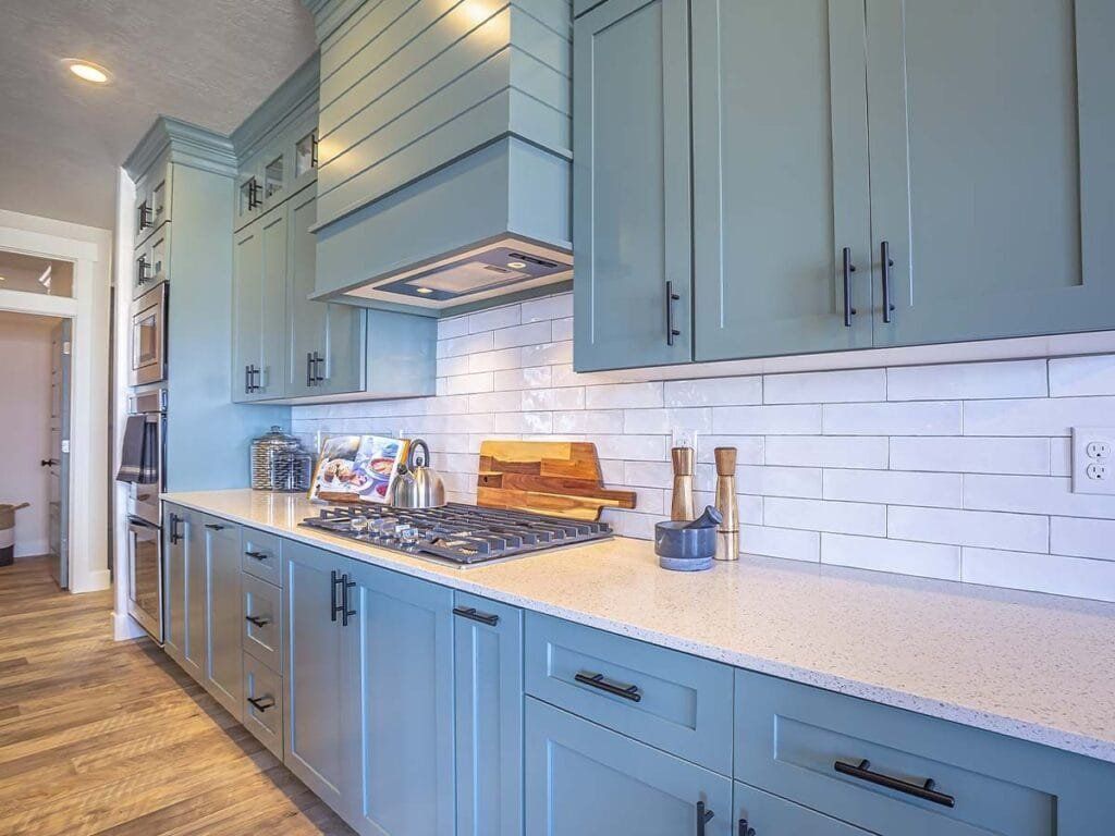 Blue kitchen cabinets with white countertops, subway tile backsplash, and stainless steel appliances.