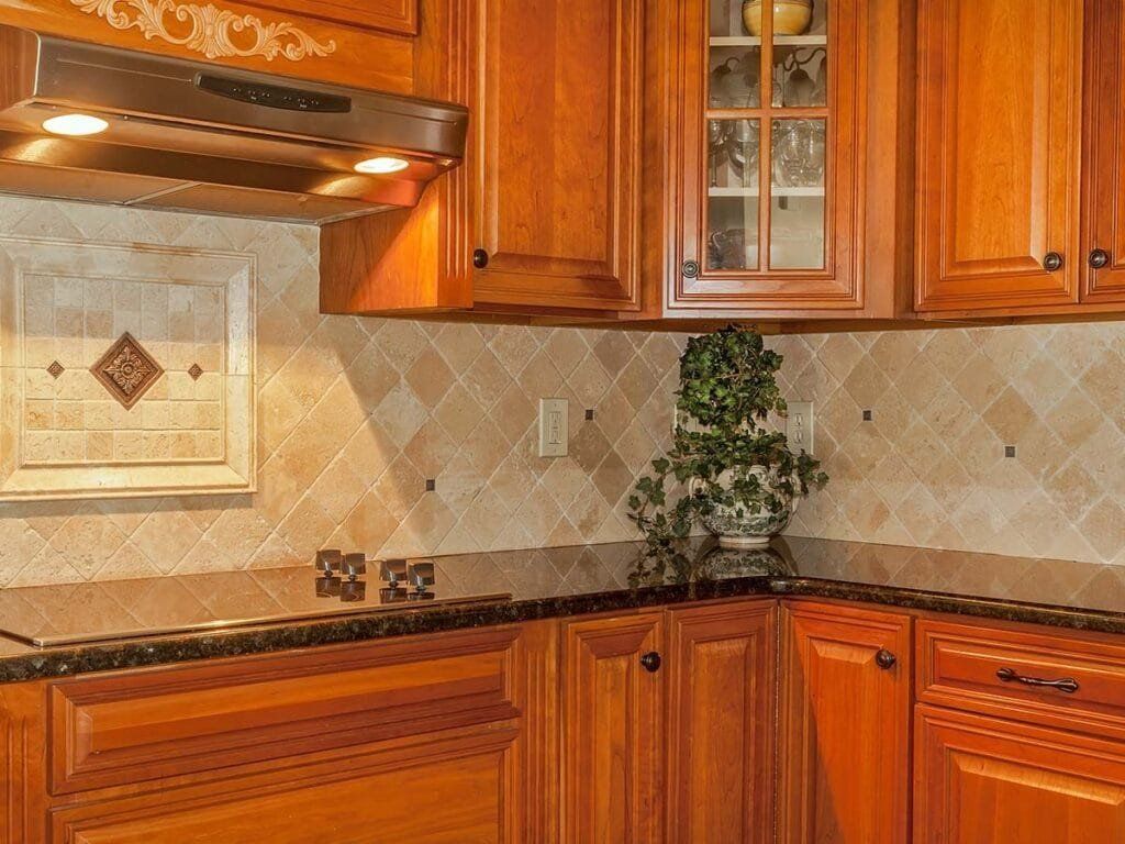 Kitchen corner with wooden cabinets, backsplash, black countertop, and a plant.