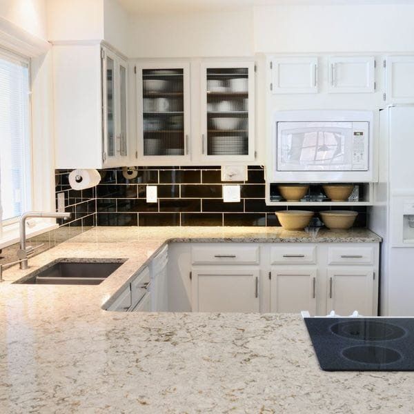 White kitchen with granite countertops, black backsplash, and built-in microwave.