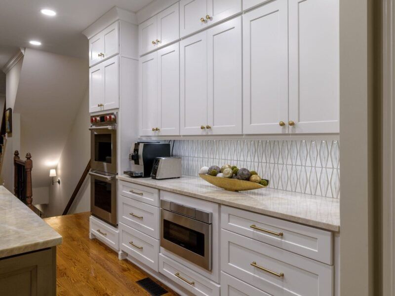 White kitchen cabinets with built-in appliances and a patterned backsplash.