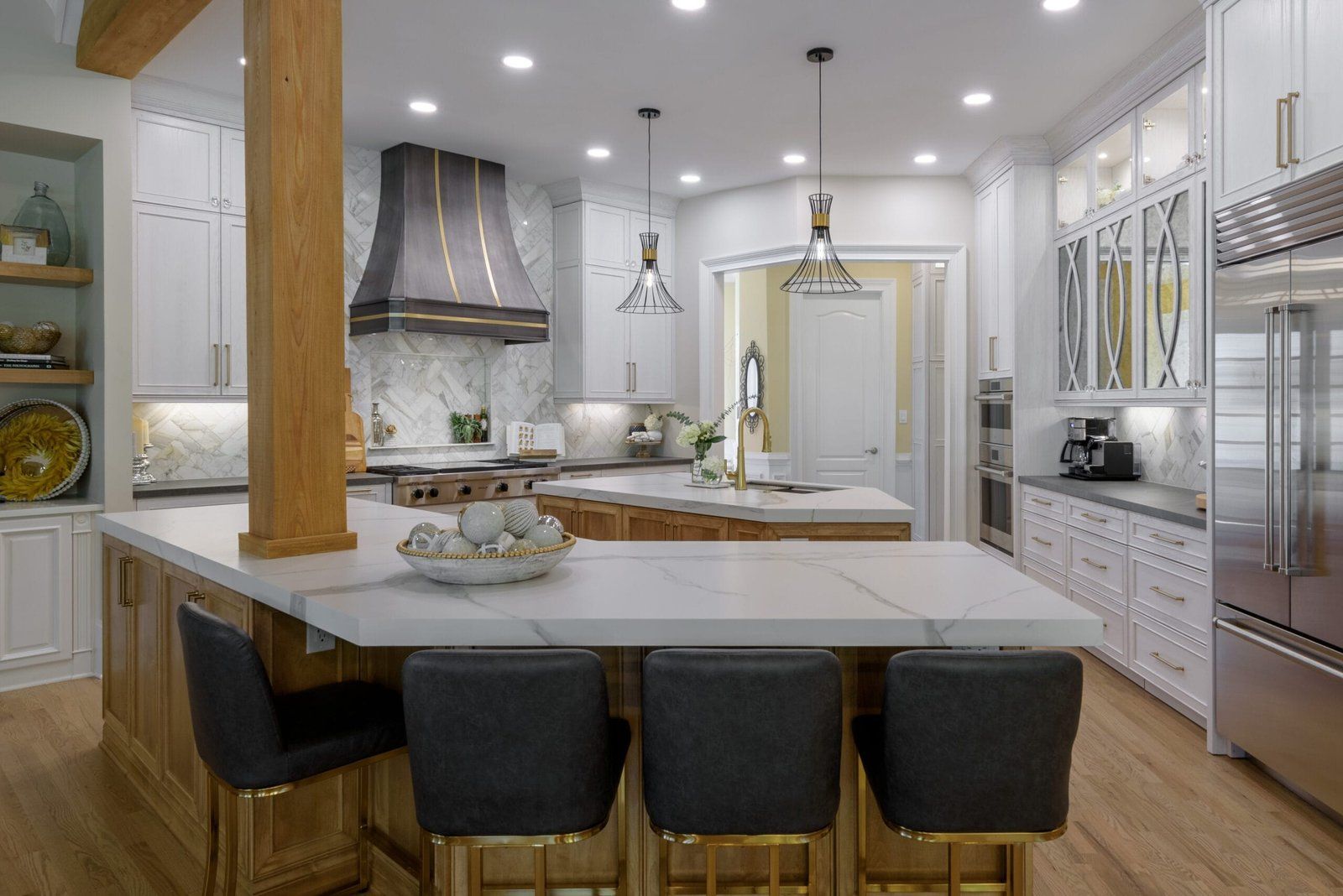 Luxurious kitchen with marble countertops, wooden cabinetry, and modern light fixtures.