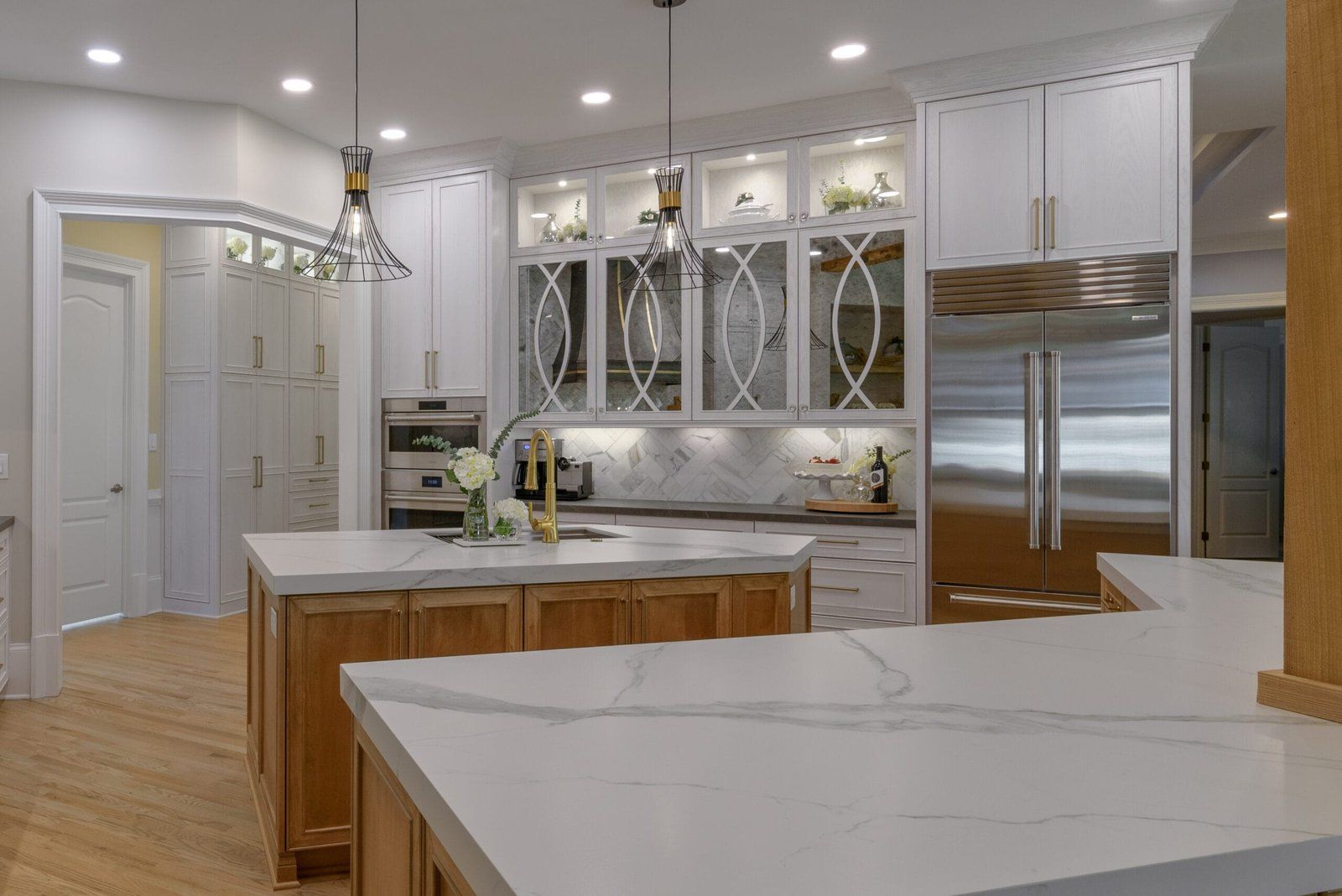 Elegant kitchen with white cabinets, marble countertops, wooden island, and stainless steel appliances.