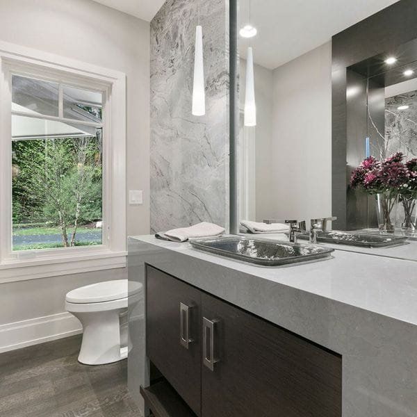 Modern bathroom with a white toilet, gray countertop, and dark wood vanity.