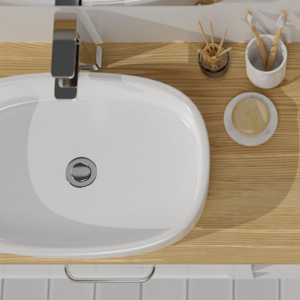 Overhead view of a white bathroom sink with a chrome faucet and wooden countertop.