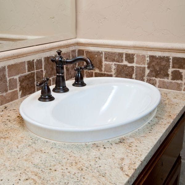 White oval bathroom sink with dark bronze faucet on a speckled granite countertop.