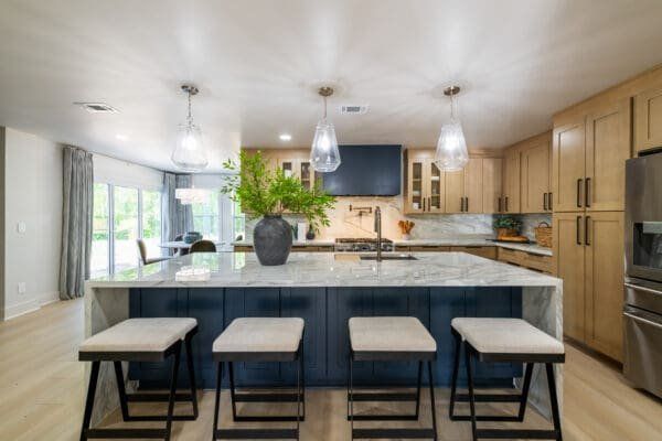 Modern kitchen with a blue island, light wood cabinets, and pendant lights.