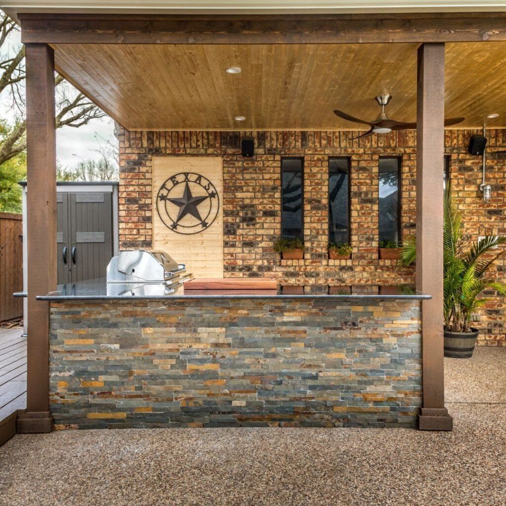 Outdoor kitchen with a stone facade, grill, bar, and Texas star decor.