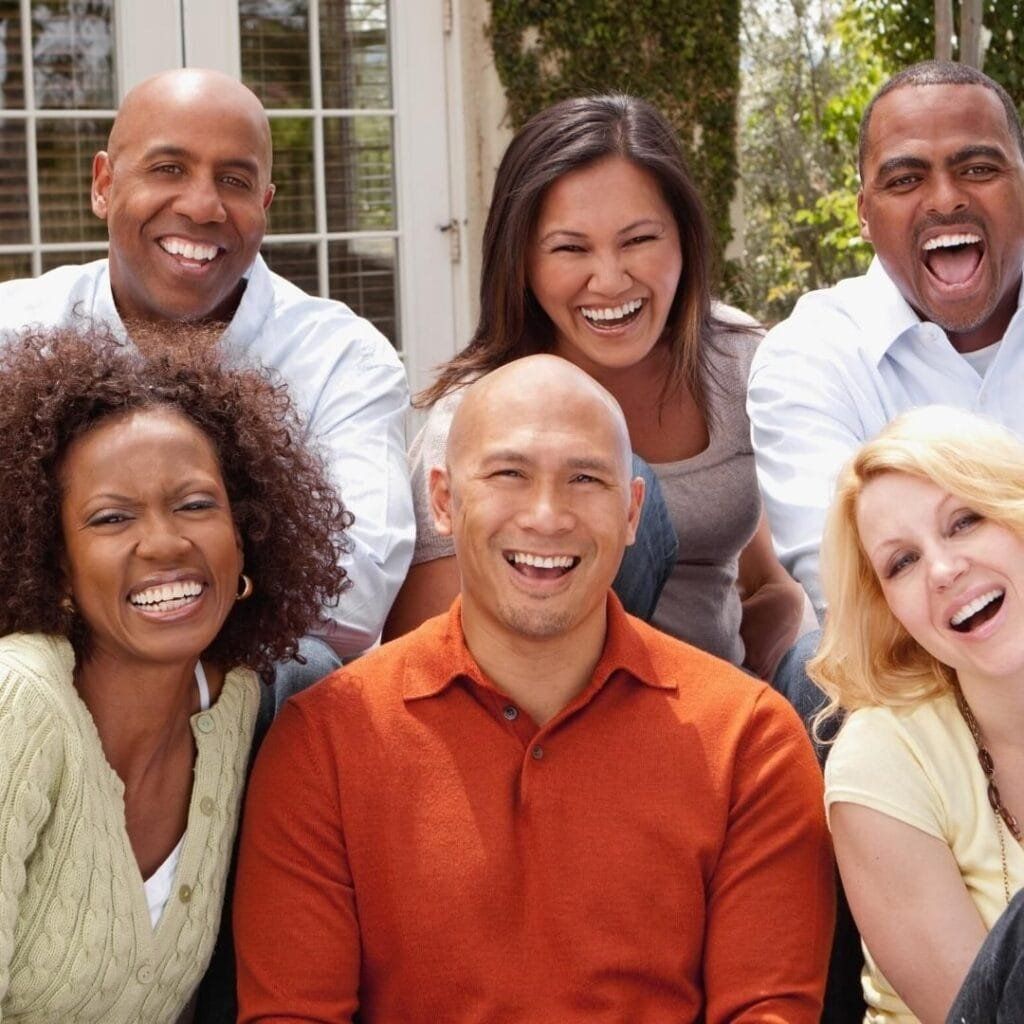 Group of people smiling and laughing together outdoors.