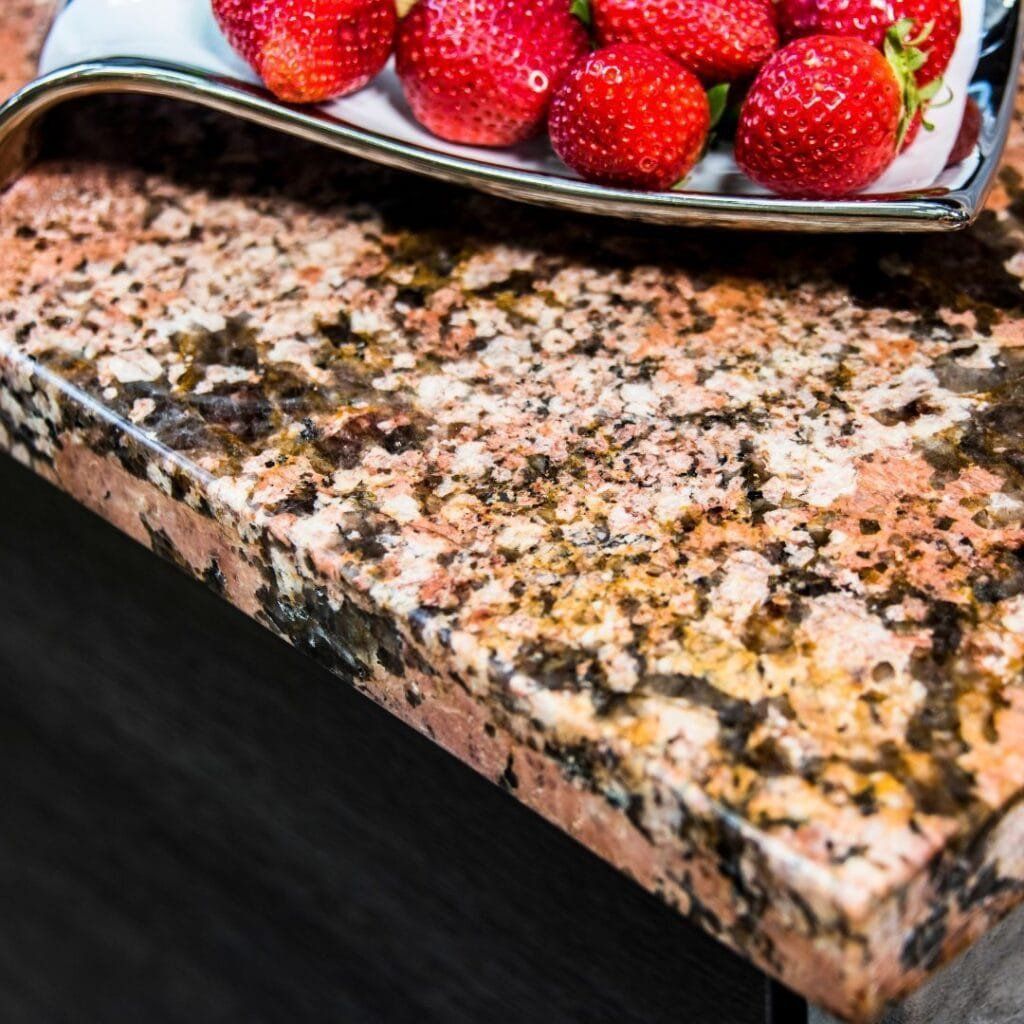 Strawberries on a decorative plate, set on a granite countertop, close-up shot.