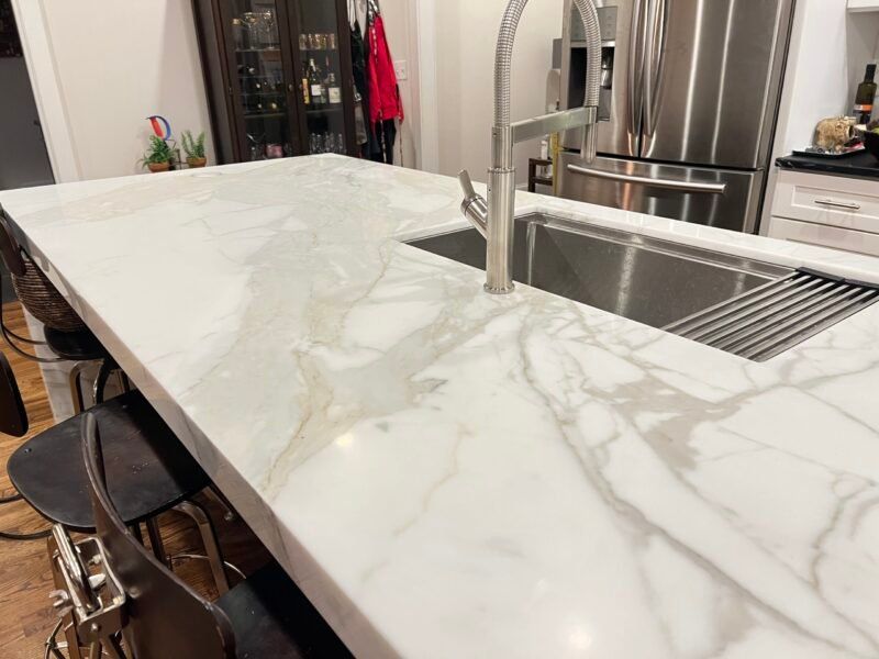 IMG_5112 White marble countertop with veining, stainless steel sink and faucet.