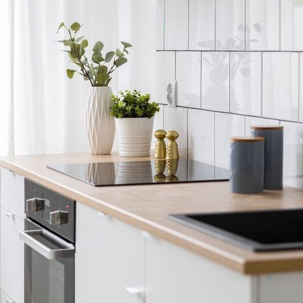 Kitchen countertop with a stove, plants, and jars.