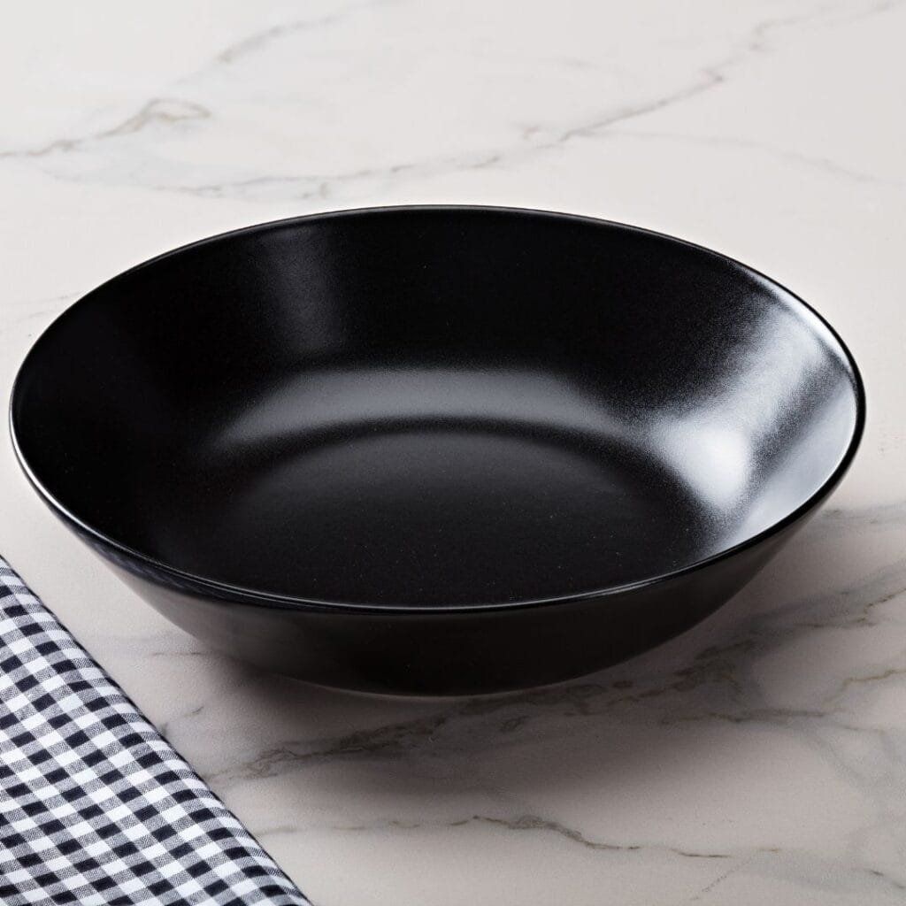 Black ceramic bowl on a marble surface, next to a checkered cloth.