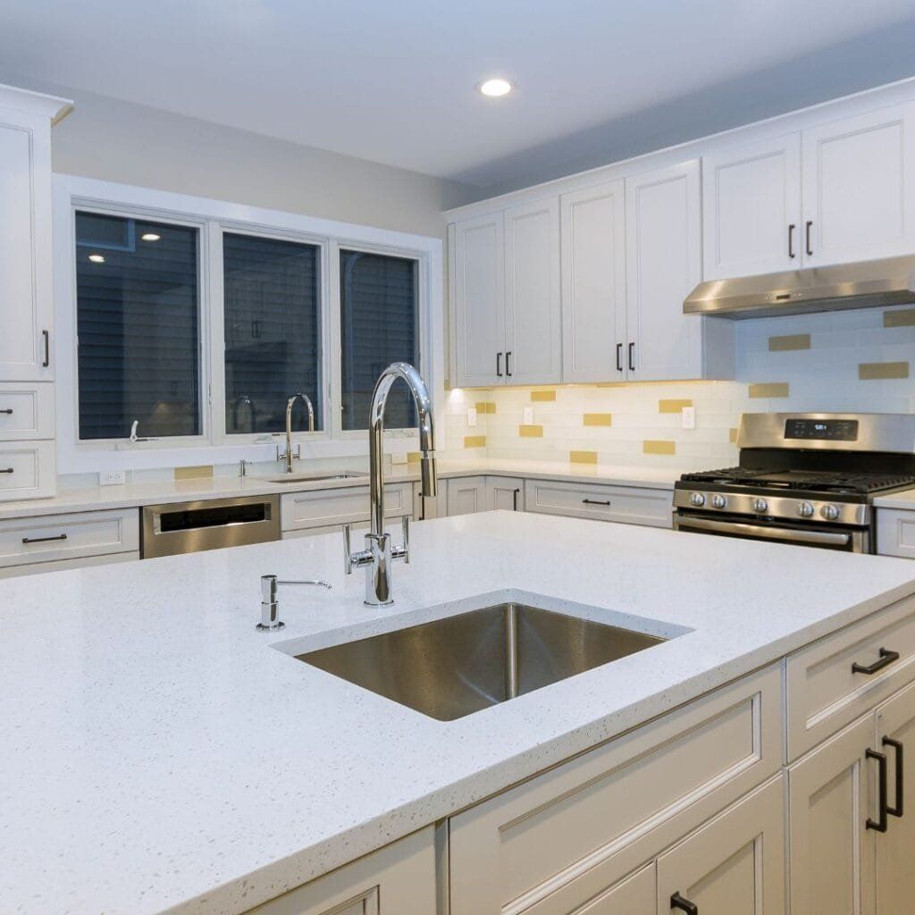 White kitchen with stainless steel appliances, a large island, and a window.