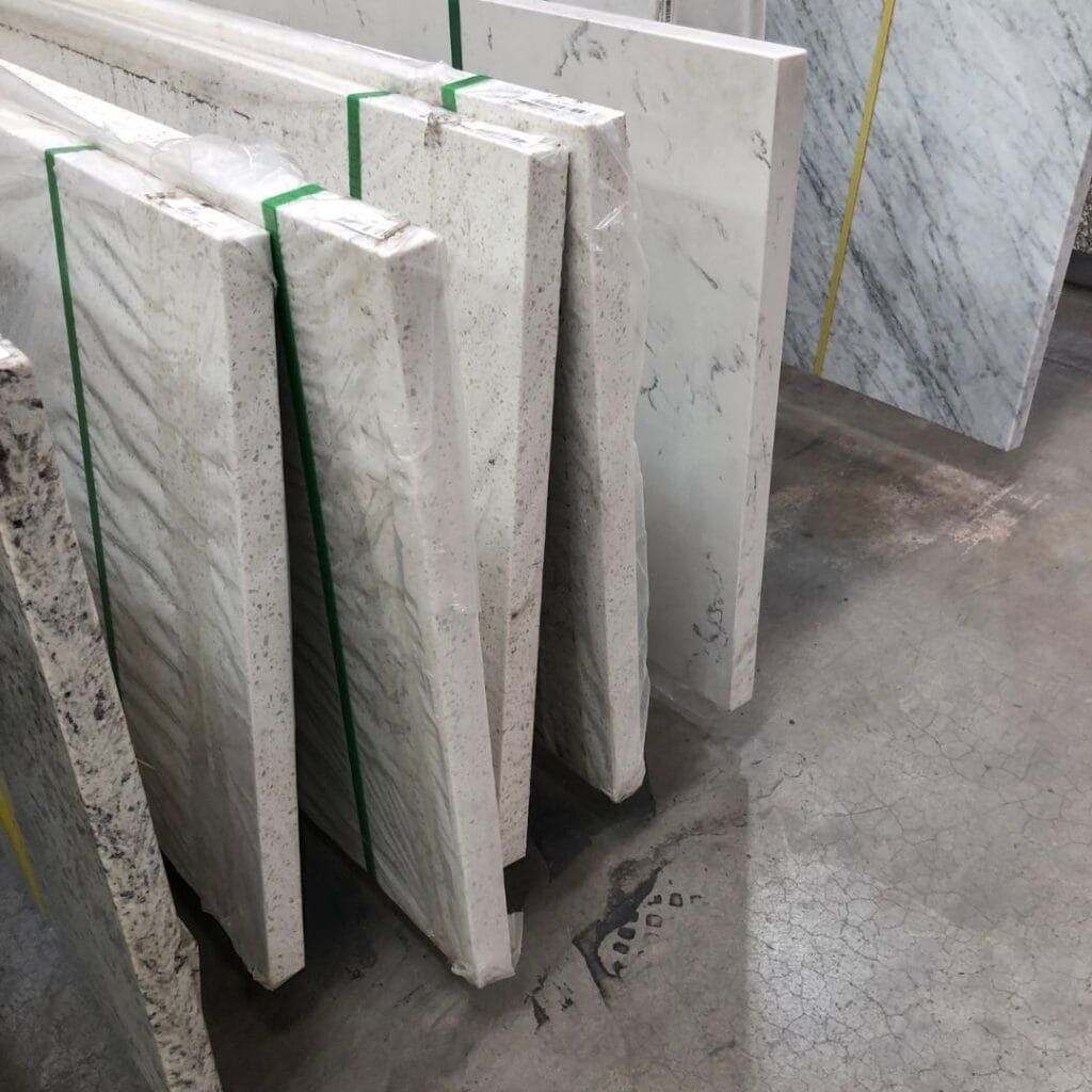Stone slabs wrapped in plastic, stacked vertically in a warehouse.