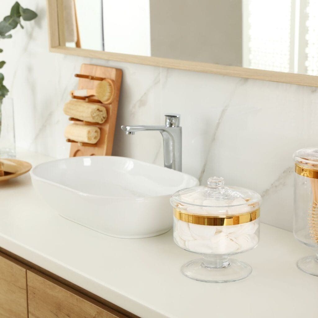 Bathroom vanity with a sink, faucet, and cotton ball jar.