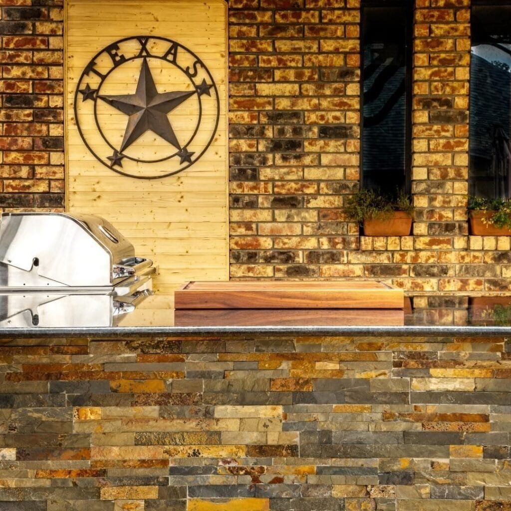 Outdoor kitchen with brick, stone, stainless steel grill, and Texas star decor.