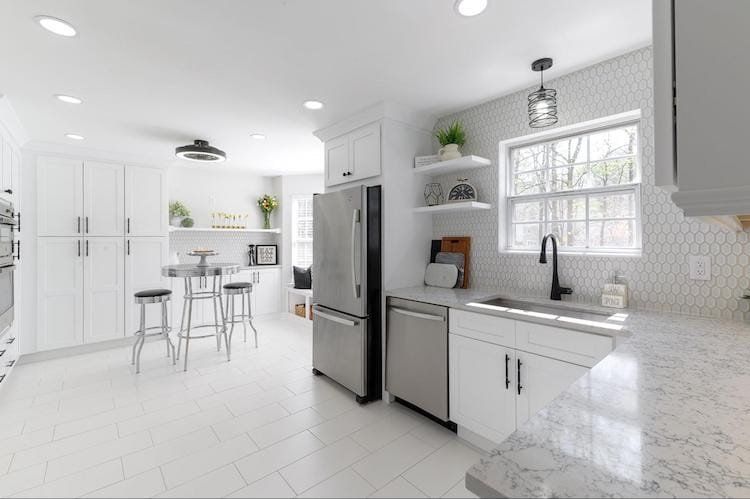Bright white kitchen with stainless steel appliances, white cabinets, and tile backsplash.