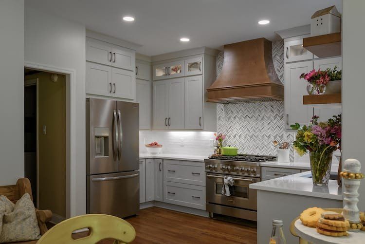 Kitchen with gray cabinets, stainless steel appliances, copper hood, and wooden floors.
