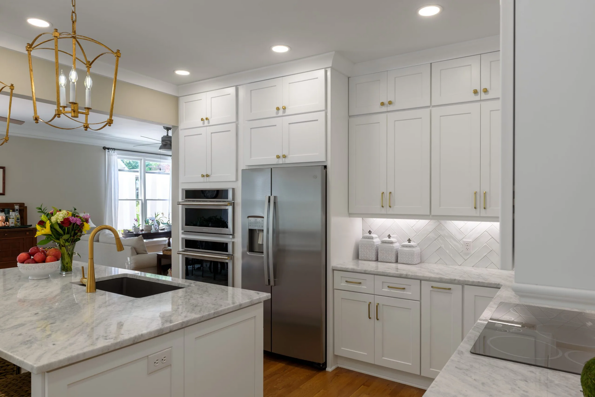White kitchen with island, stainless steel refrigerator, and gold hardware.