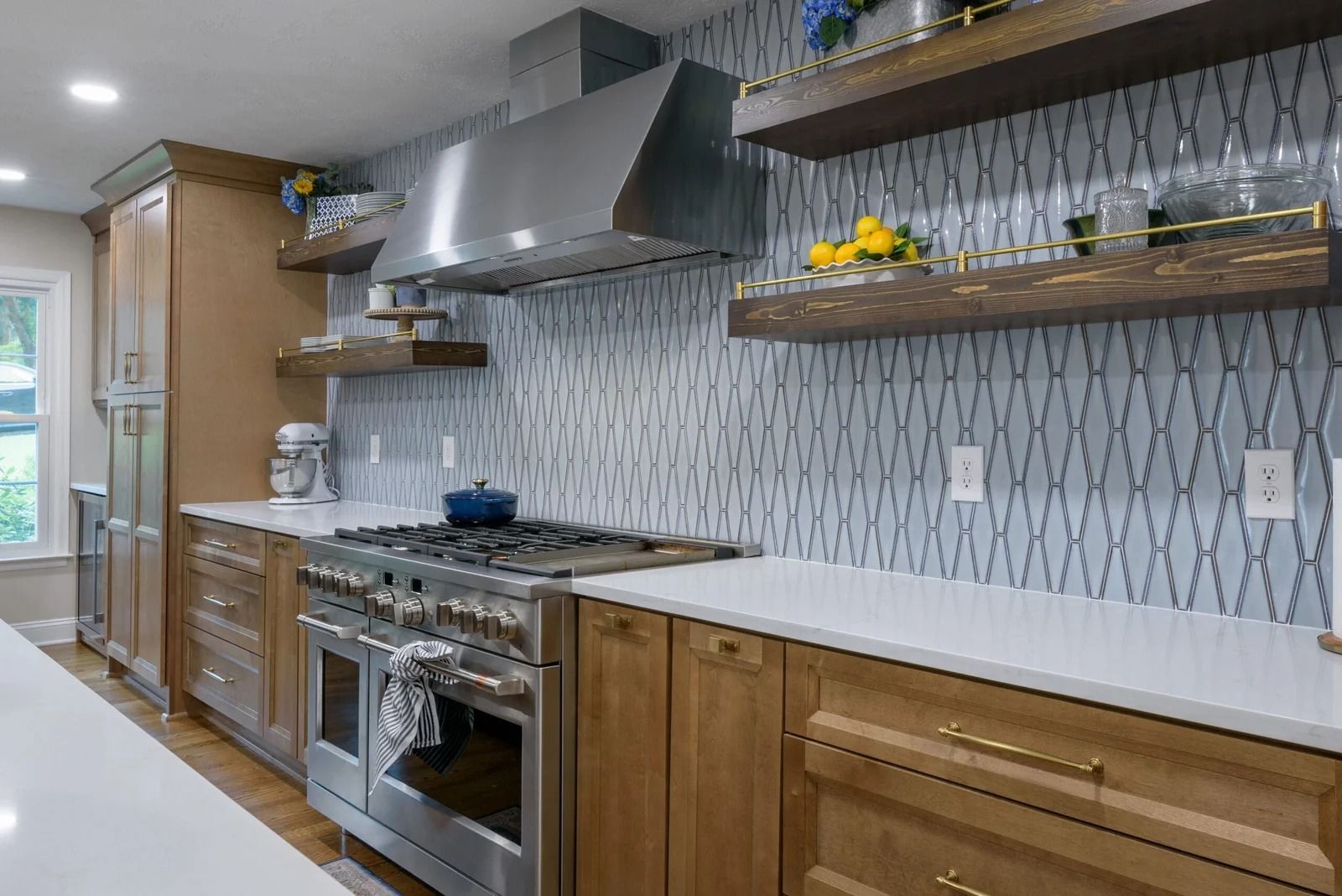 Modern kitchen with light wood cabinets, white countertops, stainless steel appliances, and patterned backsplash.