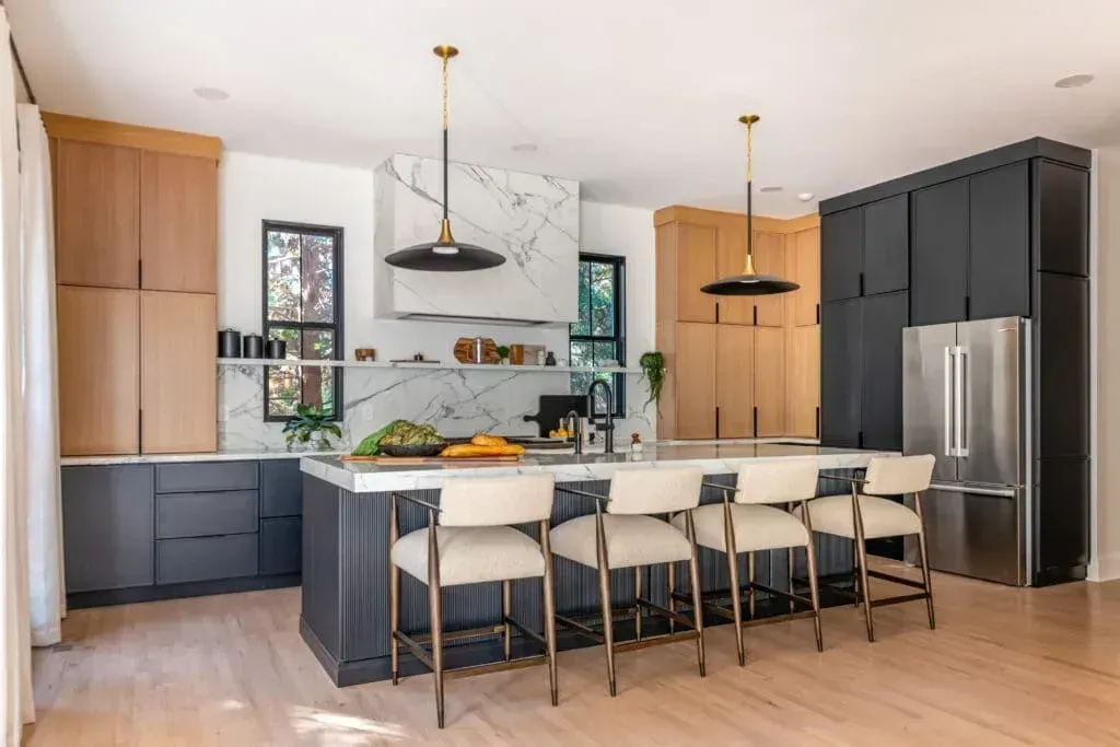 Modern kitchen with a dark blue island, light wood cabinets, and stainless steel appliances.