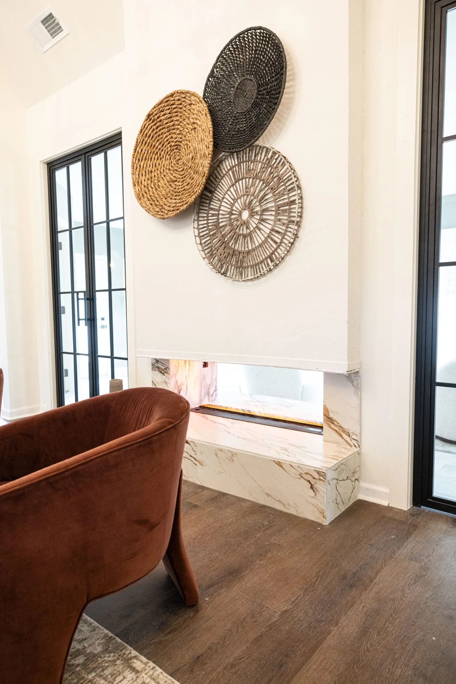 Modern living room: fireplace with three circular wall art pieces. Brown chair sits nearby.