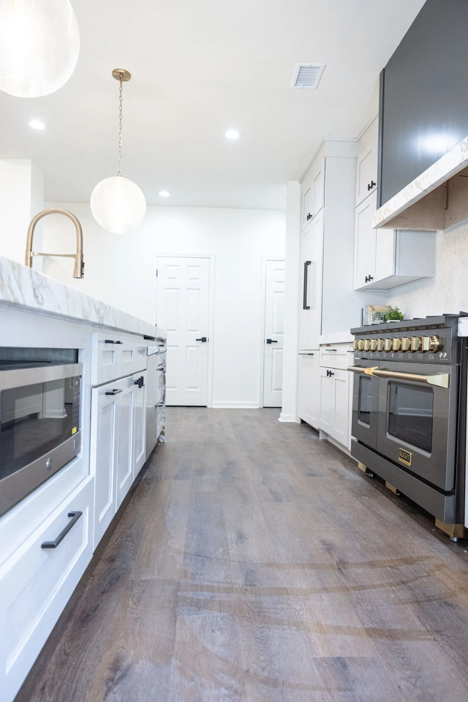 Bright, modern kitchen with white cabinets, dark wood floors, and a stainless steel stove.