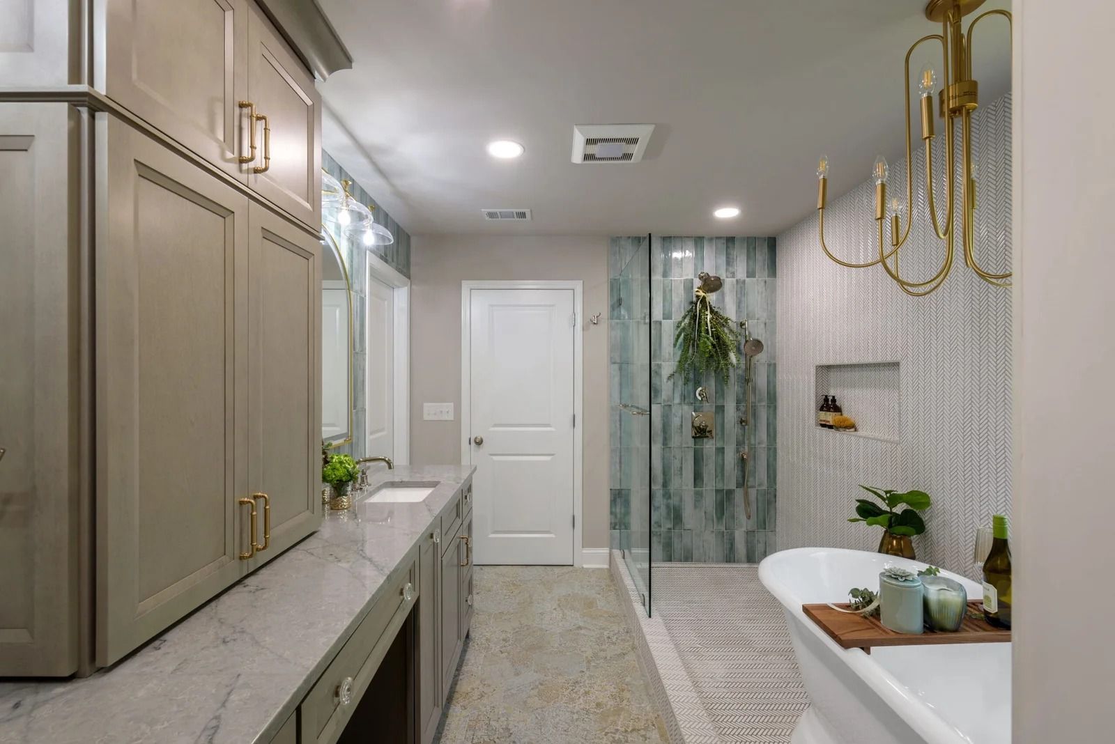 Bathroom with gray cabinets, marble countertops, white tub, and patterned tile.