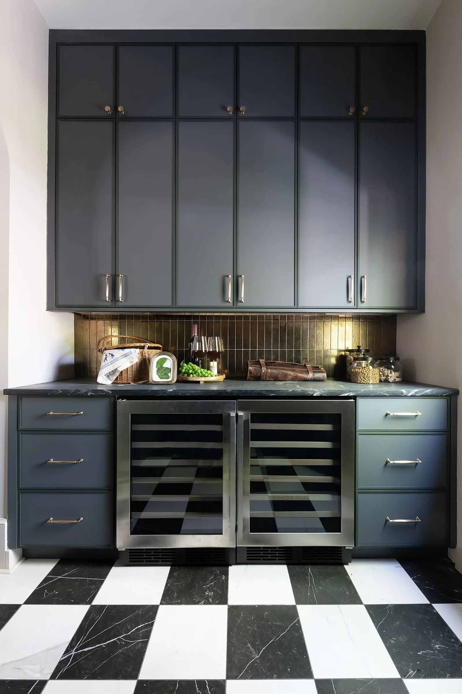 Dark gray cabinetry with wine fridge, black and white checkered floor, and bronze backsplash.