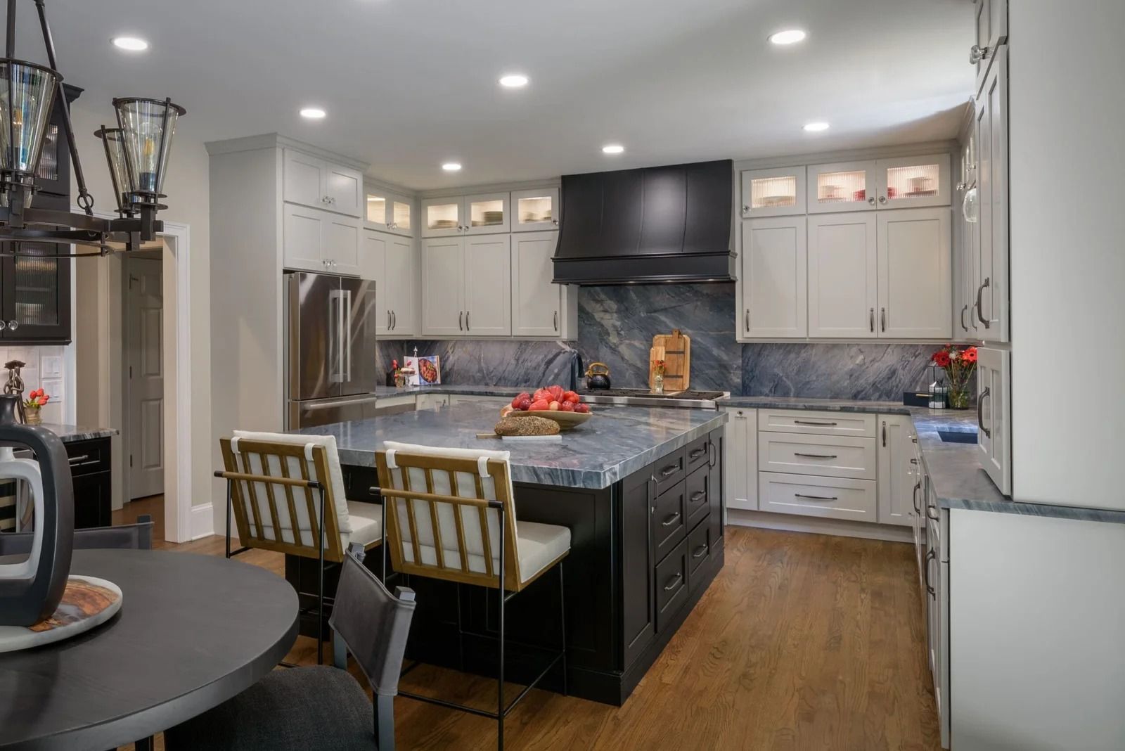 Modern kitchen with gray and black cabinets, island with stools, and dark countertops.