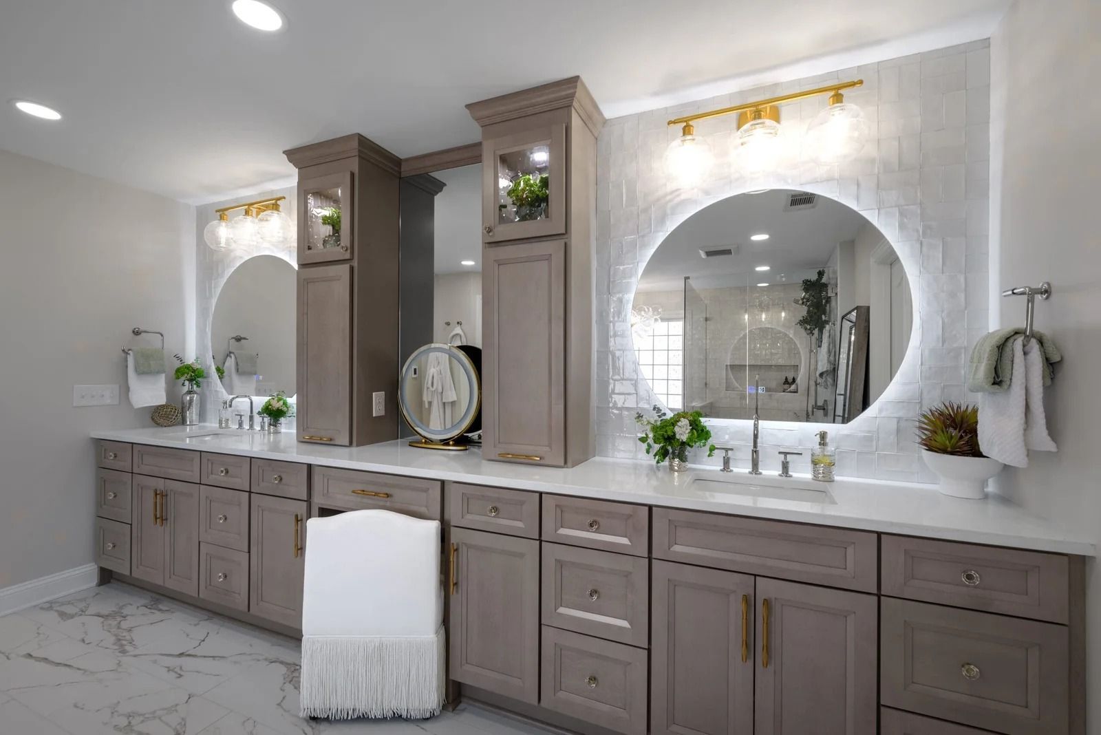 Modern bathroom with two vanities, round mirrors, and neutral cabinetry.