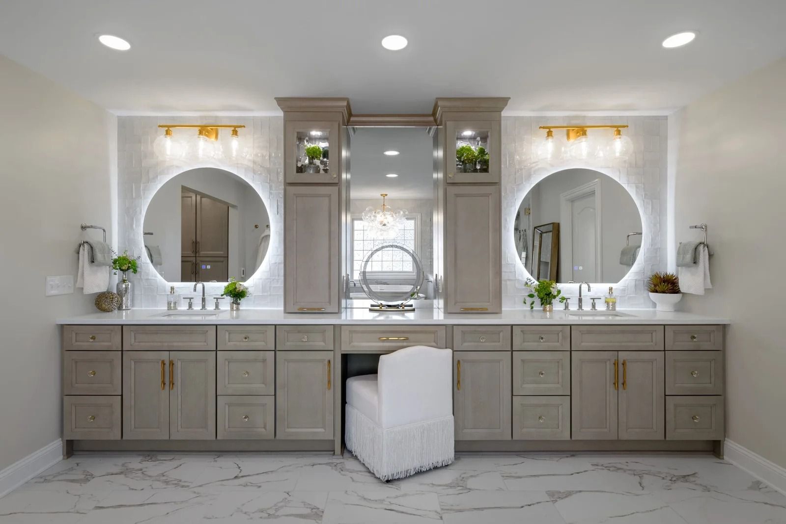A modern bathroom with a double vanity and circular mirrors, neutral colors, and gold hardware.