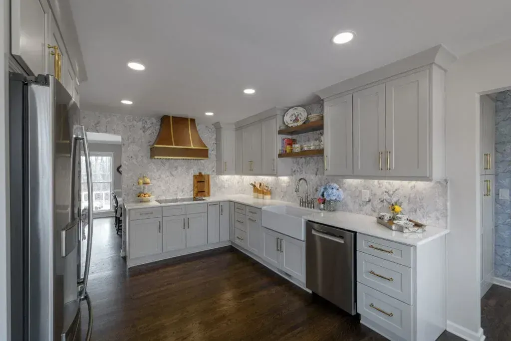 Modern kitchen with light gray cabinets, marble backsplash, stainless steel appliances, and wood floors.