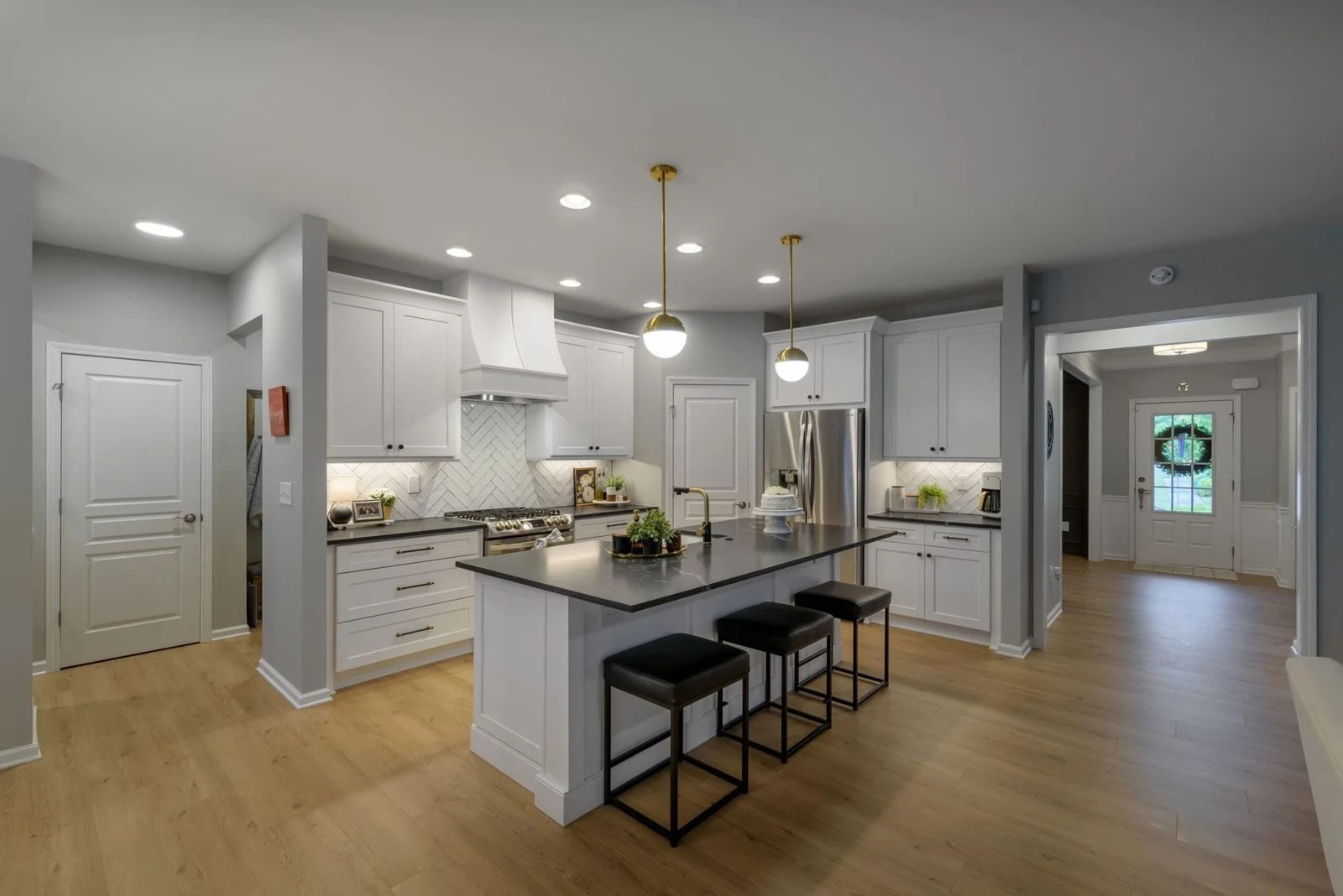 Bright kitchen with white cabinets, gray walls, island with stools, and hardwood floors.