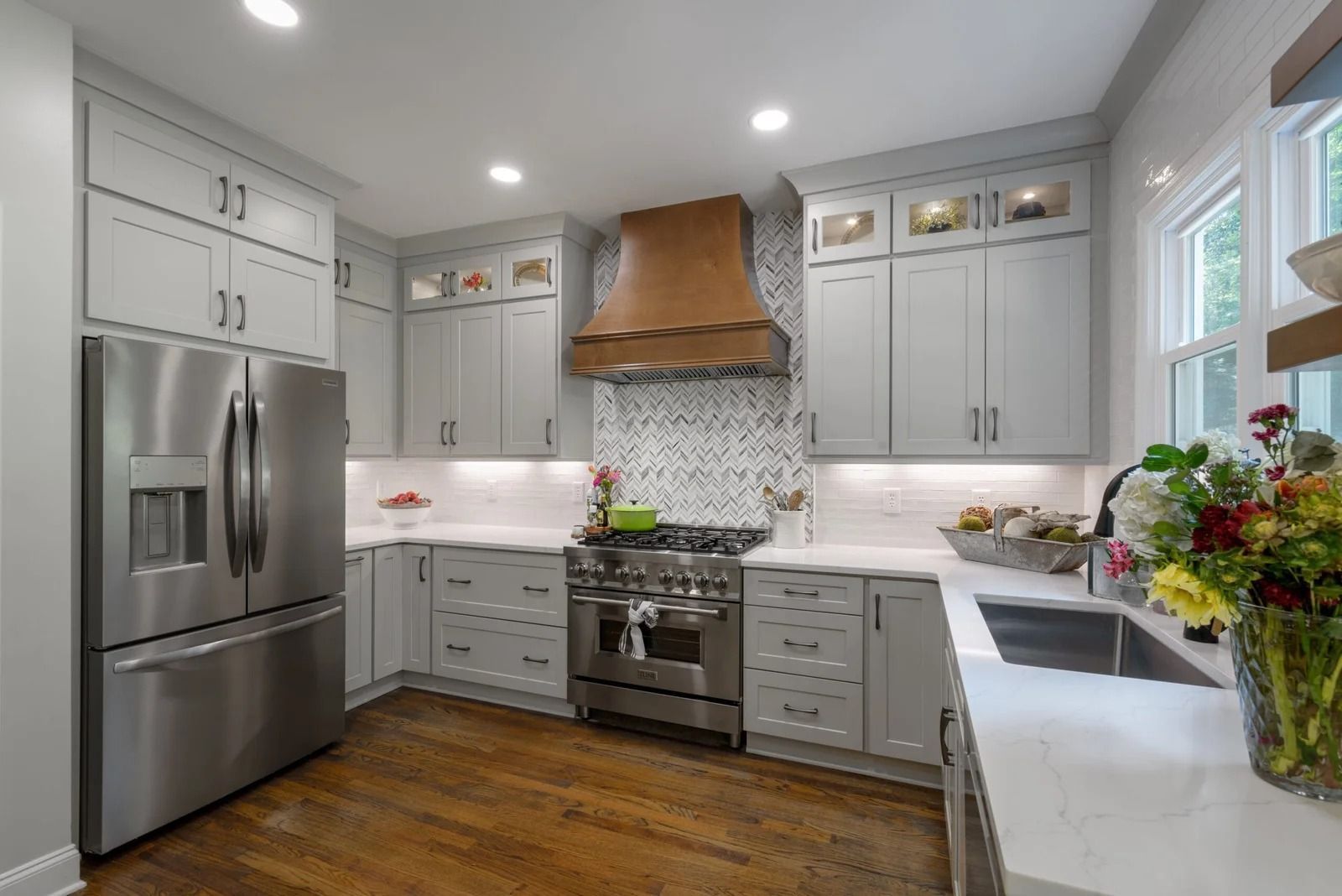 Gray kitchen with stainless steel appliances, copper range hood, and white countertops.